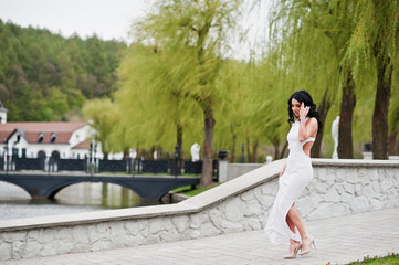Fototapeta premium Young brunette elegant woman at white dress on ceremony wedding anniversary.