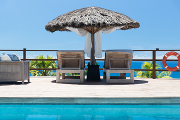 palapa and sunbeds at seaside swimming pool