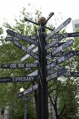 Isolated  Dramatic Upward View, Center Composition, Famous Black Signpost Directions to World Landmarks Pioneer Courthouse Square, Trees, Sky Backdrop Daytime - Portland, Oregon