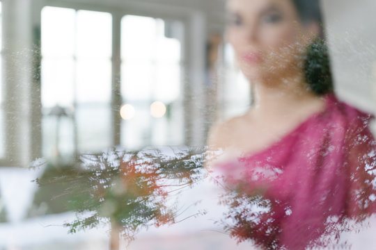 Portrait of woman in pink dress through window
