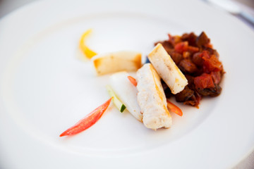 white fish with stewed eggplant garnish on plate