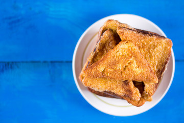 Flat lay pile of triangled french toast above blue wooden background table