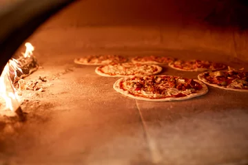 Foto auf Glas Pizza backen im Ofen in der Pizzeria © Syda Productions