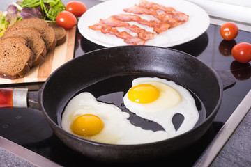 Fried bacon in a frying pan and fried egg.