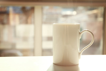 Cup of hot tea on table near window