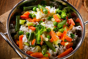 Rice with vegetables on  wooden table.