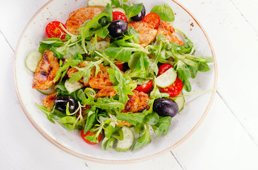 Fresh salad with chicken,  arugula, cucumber  and tomato.