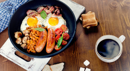 Full English breakfast with fried eggs, sausages, bacon, beans, toasts