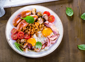 Full english breakfast with fried egg, beans, tomatoes, mushrooms, bacon, sausages