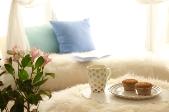 Bouquet of flowers, cup with tea and cakes in modern room