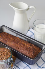 Homemade gluten free bread with linseed flour and psyllium husk. Jug and glass of milk