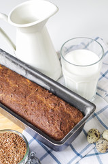 Homemade gluten free bread with linseed flour and psyllium husk. Jug and glass of milk