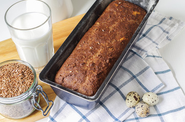 Homemade gluten free bread with linseed flour and psyllium husk. Jug and glass of milk