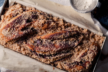 Chocolate babka on blue rustic background. Homemade cocoa bun on parchment paper with baking utensils. Traditional french cuisine
