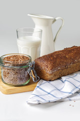 Homemade gluten free bread with linseed flour and psyllium husk. Jug and glass of milk,