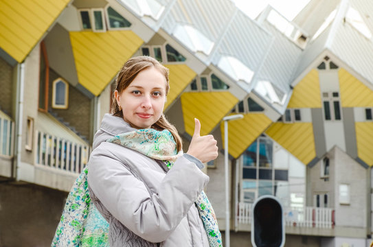 Young beautiful fashionable girl shows hand sign super on a background of Cube House Rotterdam
