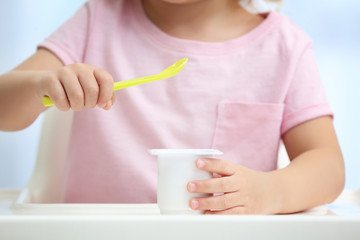 Cute little girl eating yogurt at home, closeup
