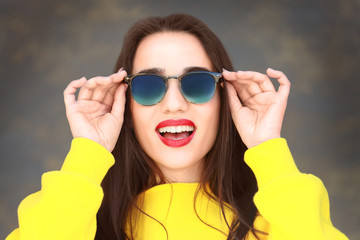 Beautiful young woman with sunglasses on color background