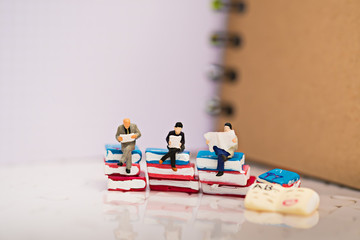 Miniature people sitting on book using as background education or business concept
