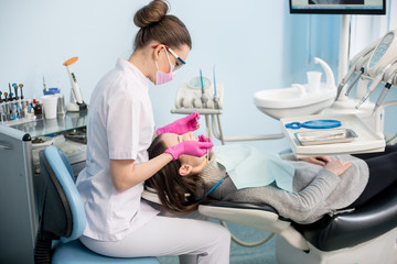 Female dentist with dental tools - mirror and probe checking up patient teeth at dental clinic office. Medicine, dentistry and health care concept. Dental equipment - Powered by Adobe