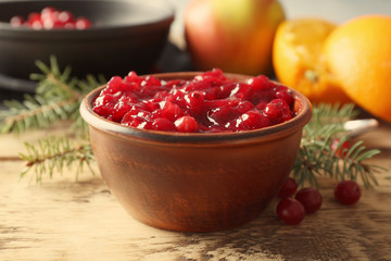 Delicious cranberry sauce in bowl on wooden background, close up