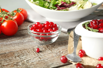 Delicious cranberry sauce in bowl on wooden background