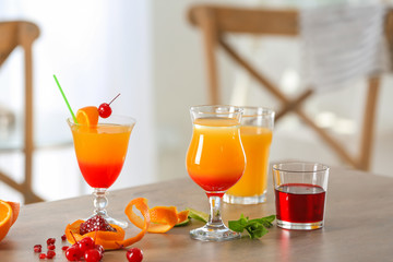 Glasses of Tequila Sunrise cocktail with ingredients on table