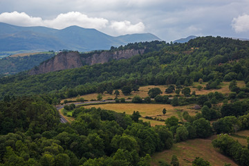 Fototapeta premium Panoramic view of mountain landscape and road through volcanic terrain at the volcanoes regional natural park in Auvergne, France