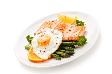 Griilled salmon with asparagus and fried egg on white background