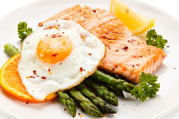 Griilled salmon with asparagus and fried egg on white background