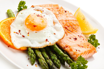 Griilled salmon with asparagus and fried egg on white background