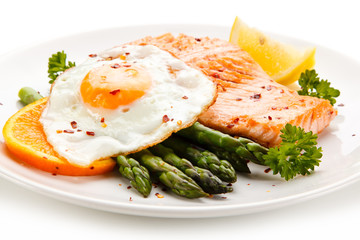 Griilled salmon with asparagus and fried egg on white background