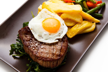 Grilled steak with french fries and fried egg