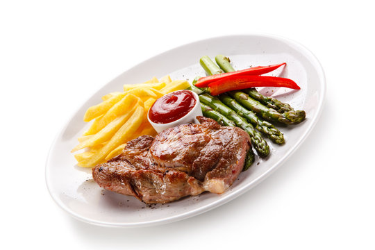Grilled steak with french fries and asparagus on white background