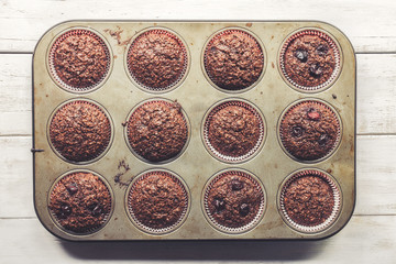 Chocolate bran muffins with cherries, in old, grunge looking, tin tray, top view, detail