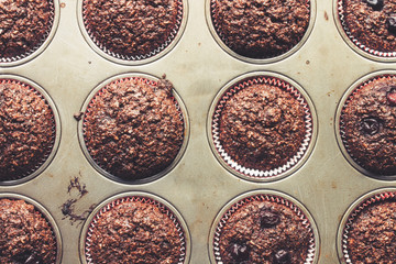 Chocolate bran muffins with cherries, in old, grunge looking, tin tray, top view, detail