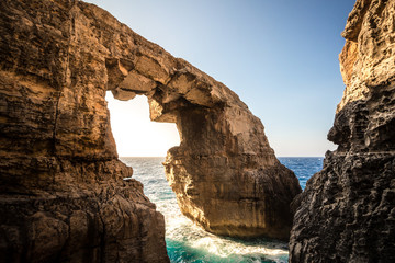 The stone sea arch at wied il-Mielah, Gozo, Malta. Sunny weather, bright sunlight golden hour.