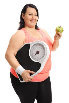 Overweight woman holding a weight scale and an apple
