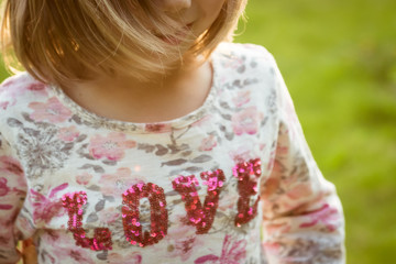 Smiling girl with developing hair in a t-shirt with the inscription Love. Crop. Selective focus