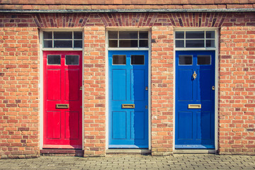 Three differently coloured front doors at the entrance of old English terraced houses. Canterbury,...