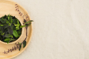Fototapeta na wymiar Basil leaves and flowers in wooden bowl from top view with copy space