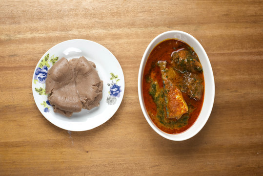 A bowl of amala served with a soup of meat and fish in ewedu and gbegiri sauce