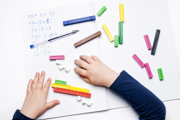 Open exercise book with colored plastic math learning tools number rods on white background....