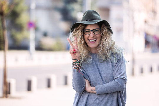 Happy hipster woman wearing hat and glasses in the city summer.