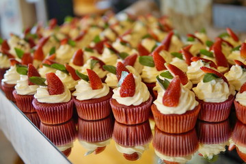 Luxurious wedding cupcakes in red and white color and with strawberry at the top 