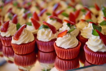 Luxurious wedding cupcakes in red and white color and with strawberry at the top 