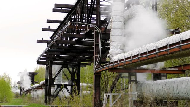 industrial pipelines on pipe-bridge from which emanate jets of steam