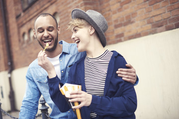 Young woman feeding boyfriend with French fries