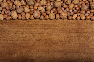 Variation of walnuts and hazelnuts on a wooden background