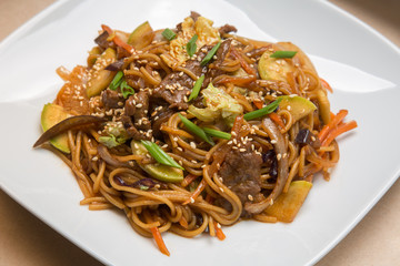 Chinese noodles with beef on a white plate in a restaurant